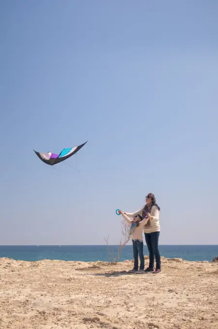 Family playing with kite by the sea