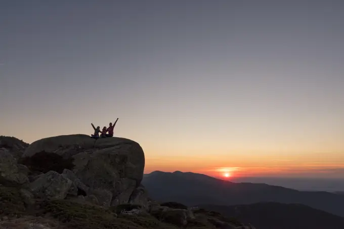 Mother and daughter watching the sunset on the top of the mountain