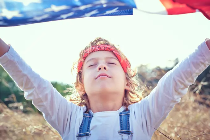 Boy in nature holding an American flag