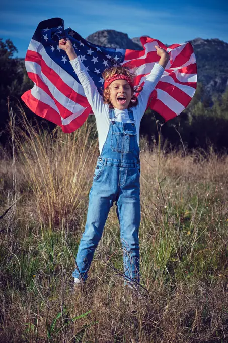 Boy in nature holding an American flag