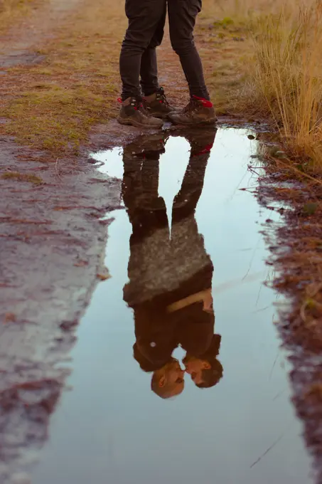 Water slop with reflection of homosexual couple embracing and kissing on road