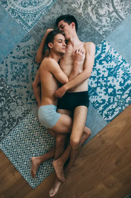 Passionate sexual naked gay couple in an intimate moment lying down in a rug at home