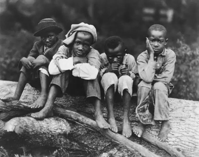 Four boys sitting on a log