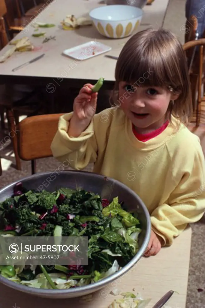 Portrait of a girl showing a green pea pod