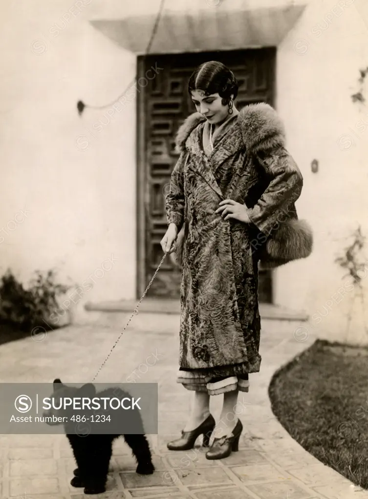 Elegant woman holding bear cub on leash