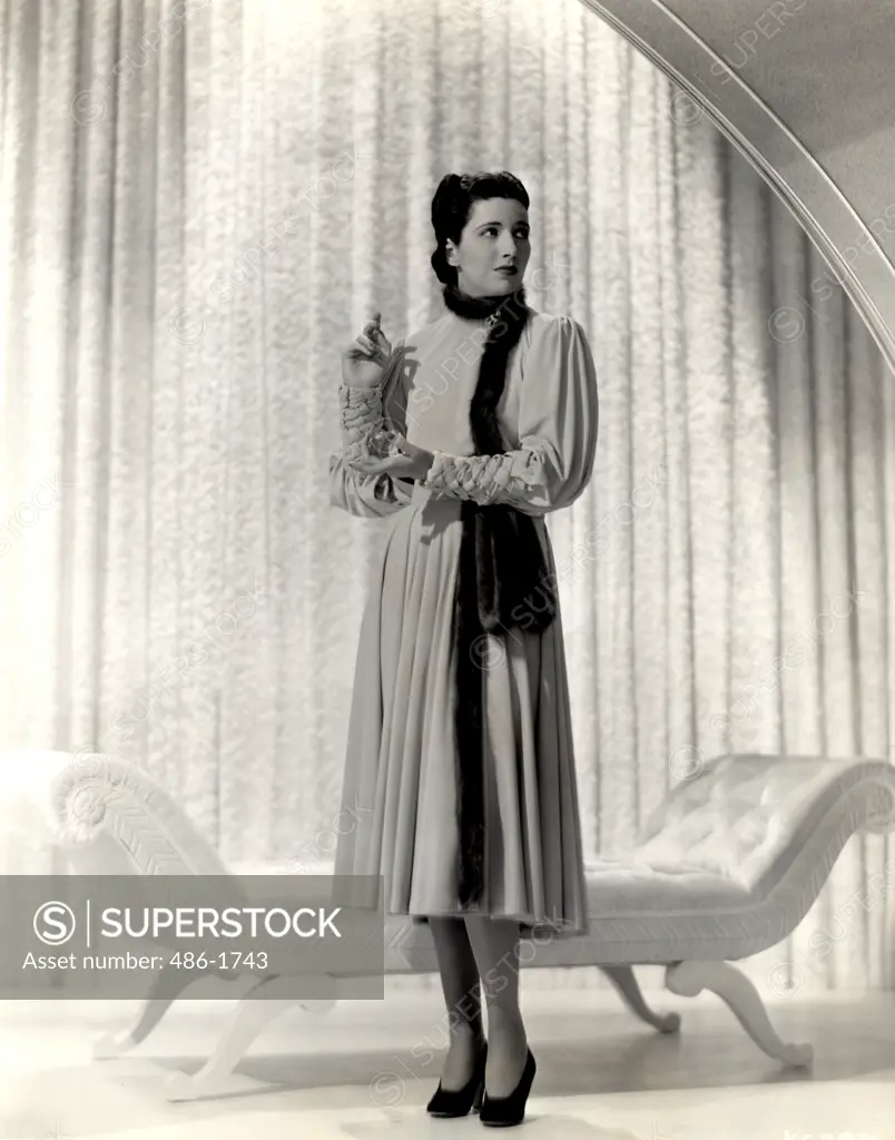 Fashion model posing against curtain, 1931