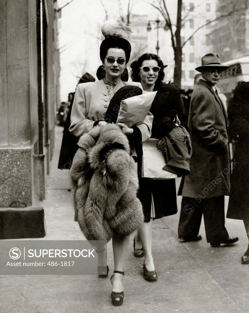 Elegant mid adult women walking on street, man looking back at them