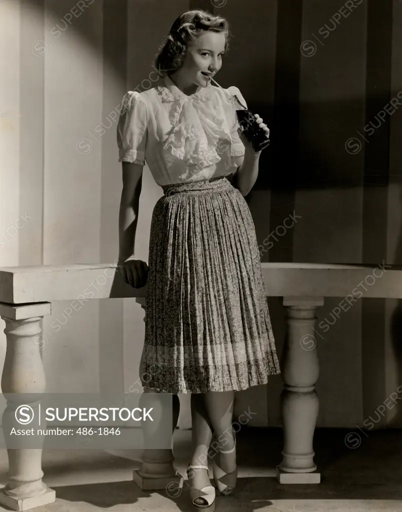 Studio shot of fashion model in casual clothing drinking soda