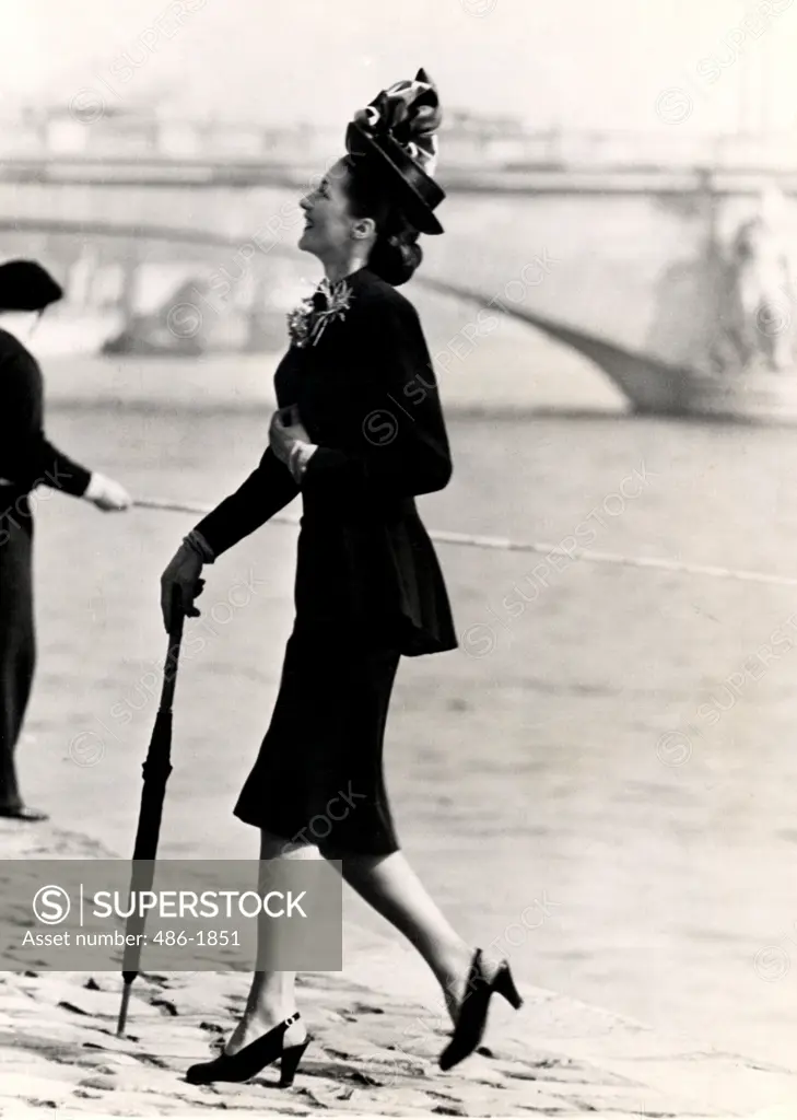 Mid adult woman walking on riverbank in elegant clothing