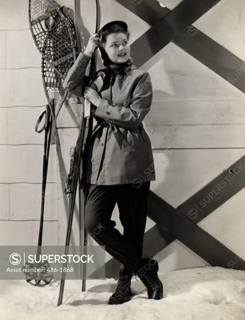 Portrait of young woman wearing ski clothing, leaning on skies