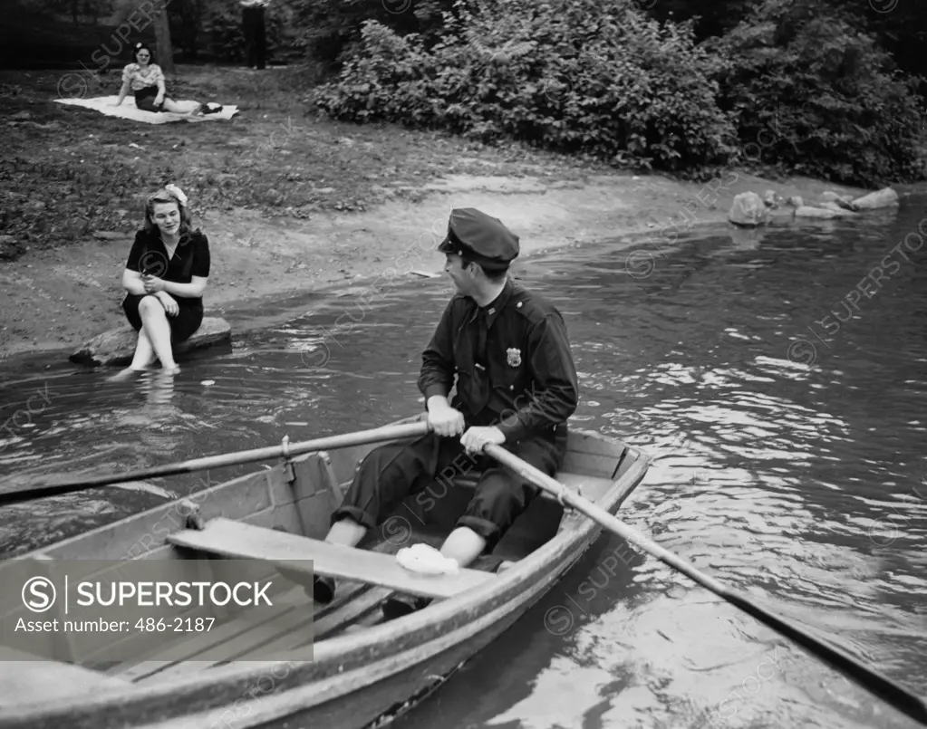 USA, New York City, Central Park, Police Officer Talking To Woman From Boat, 1944, Central Park, Patrolman Miller Warns A Girl To Keep Her Feet On Dry Land. Who Knows What Might Come Along A Shark, Or Maybe Even A Wolf. This Isn't Just Bureaucratic Nonsense-The Water Isn't Consider Clean Enough To Swimming Or Wading. 1944