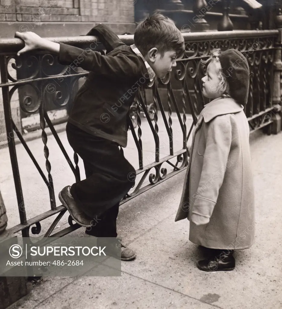 Boy and girl standing face to face next to railing