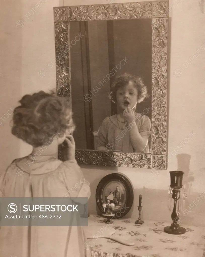 Girl looking at her reflection in mirror, mouth open