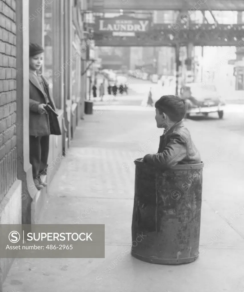 Boy sitting in barrel in street