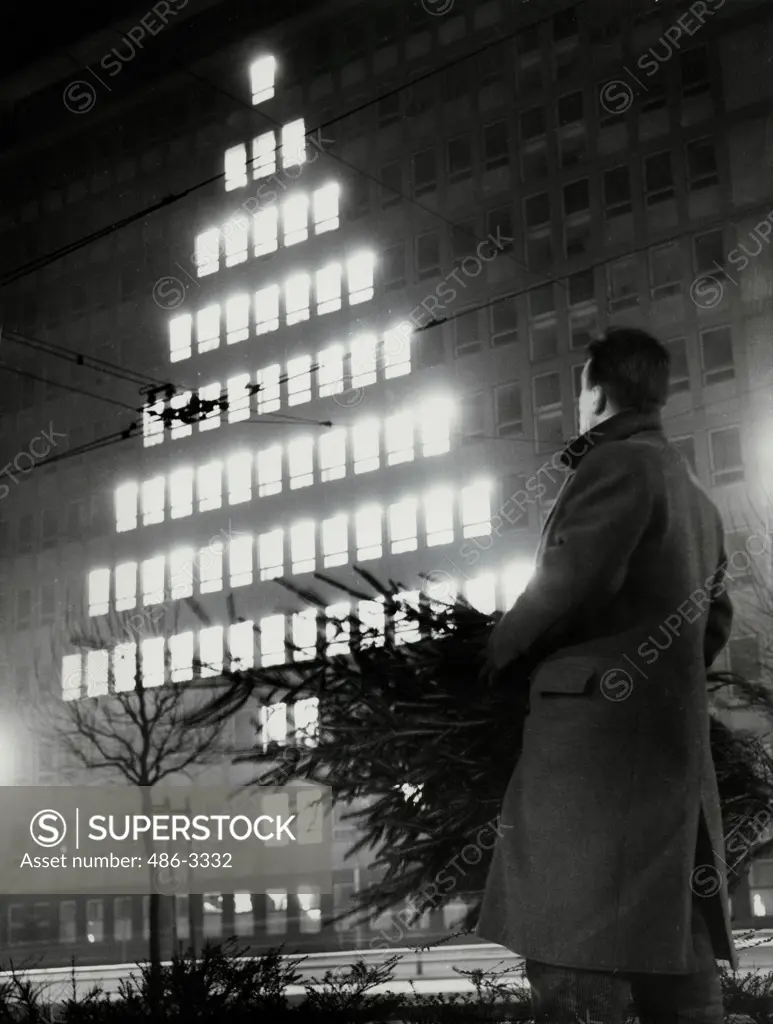 Germany, Frankfurt, Man looking at window lights in shape of Christmas tree