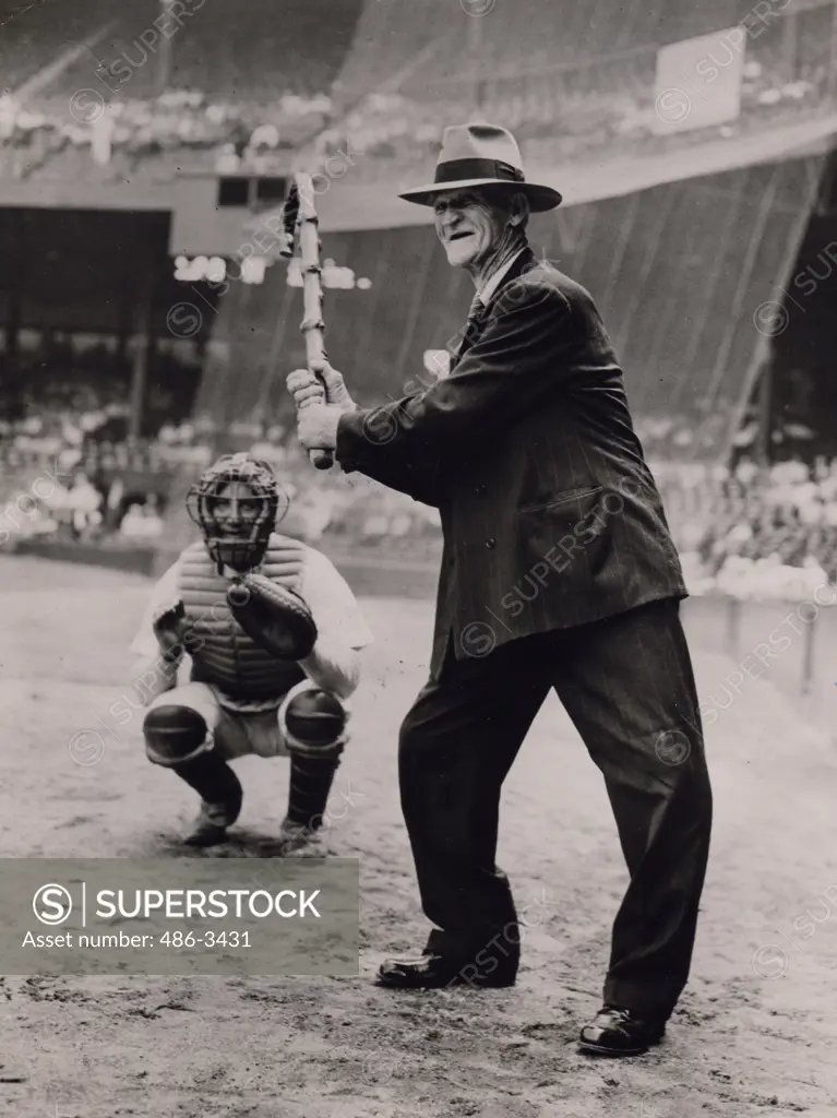 Senior man wearing full suit playing baseball with his walking stick