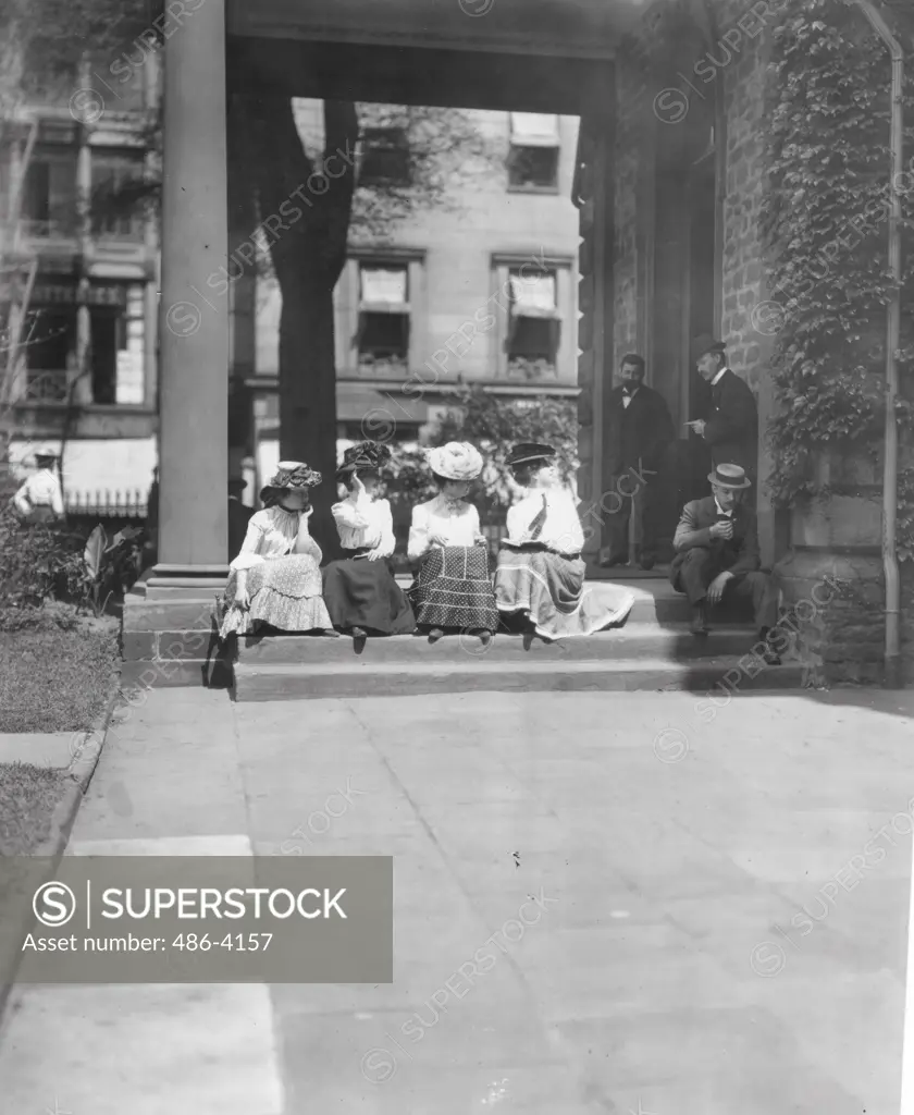 Young women sitting on steps looking at men