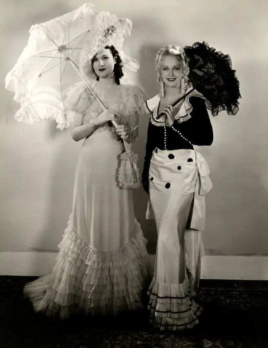 Portrait of two women in elegant clothing holding parasols