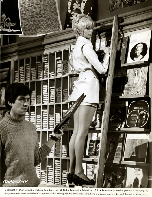 Woman climbing ladder in shop, 1969