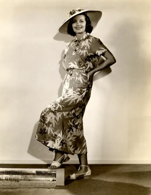 Studio shot of young woman in straw hat and dress