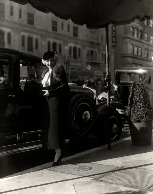 Portrait of young woman in evening dress standing by car