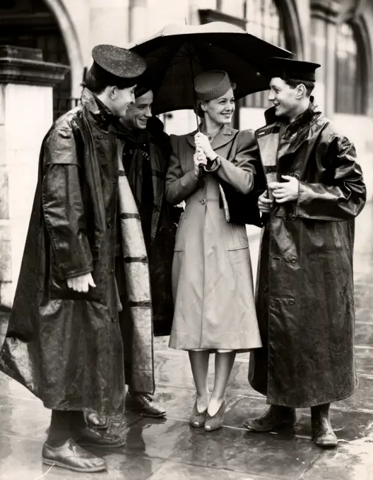 Woman with umbrella and three men in raincoats talking, 1931