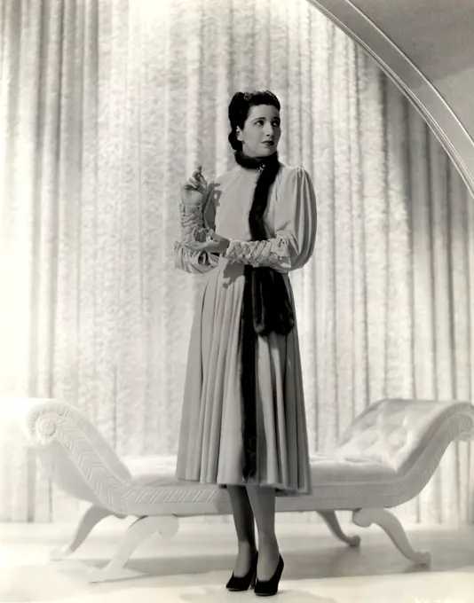 Fashion model posing against curtain, 1931