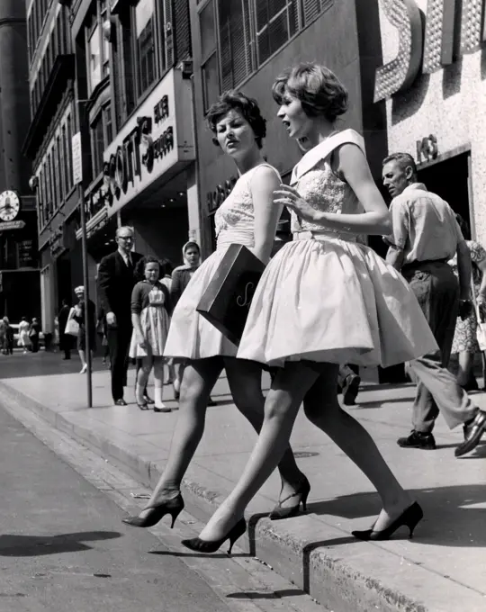 Two fashion models crossing street, side view