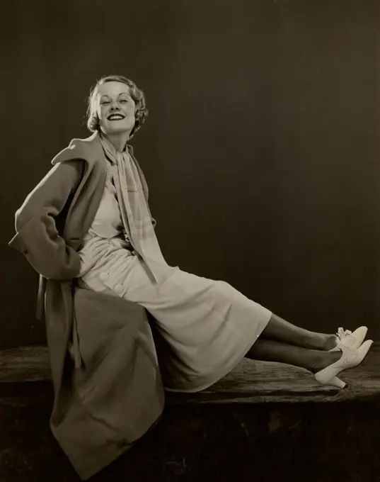 Young woman sitting cross-legged in coat, smiling