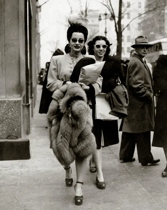 Elegant mid adult women walking on street, man looking back at them