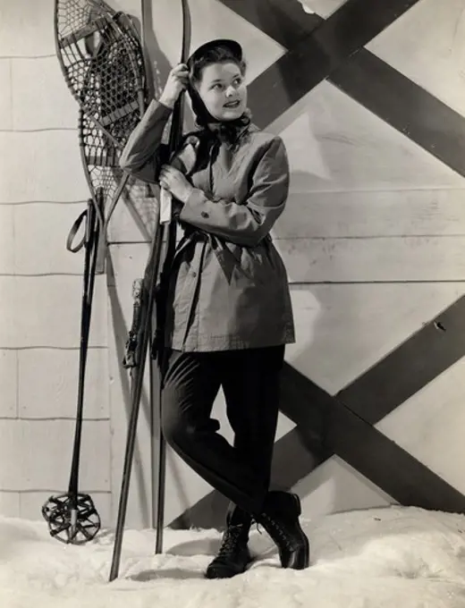 Portrait of young woman wearing ski clothing, leaning on skies