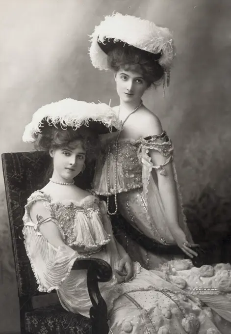 Portrait of a young woman sitting with another young woman standing by her side