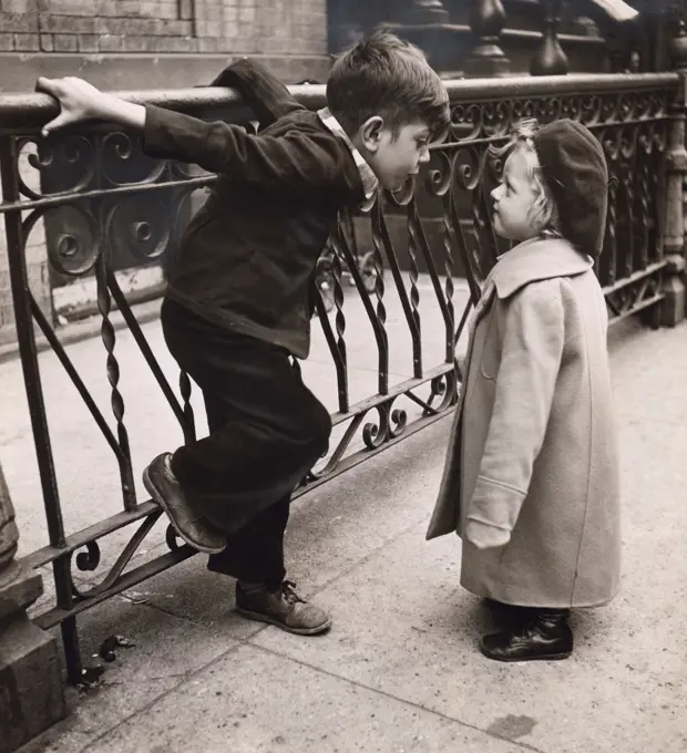 Boy and girl standing face to face next to railing