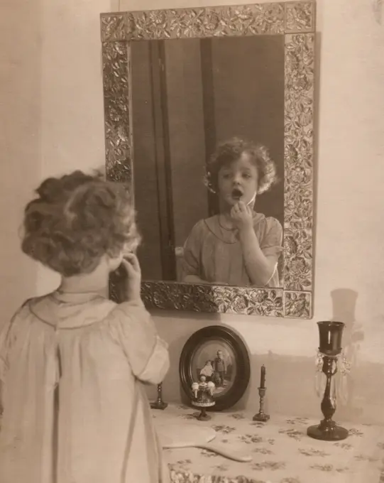 Girl looking at her reflection in mirror, mouth open