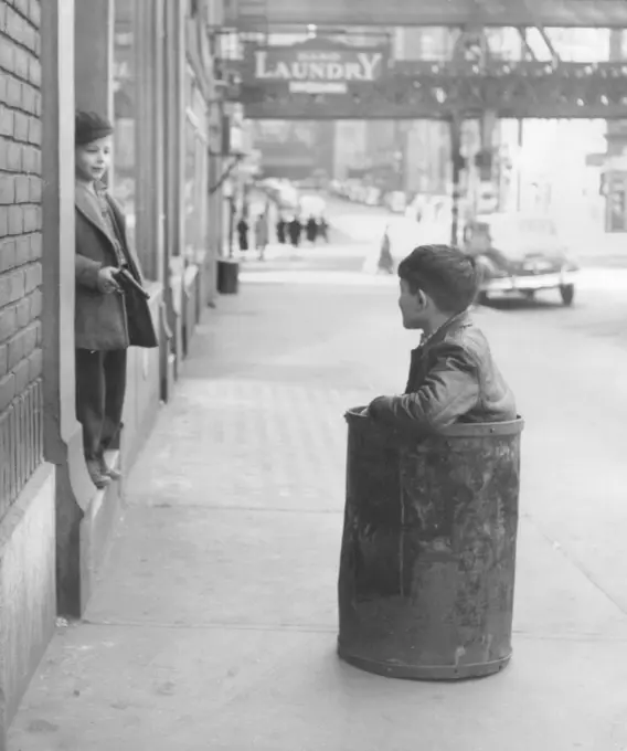 Boy sitting in barrel in street