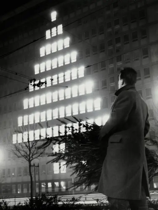 Germany, Frankfurt, Man looking at window lights in shape of Christmas tree