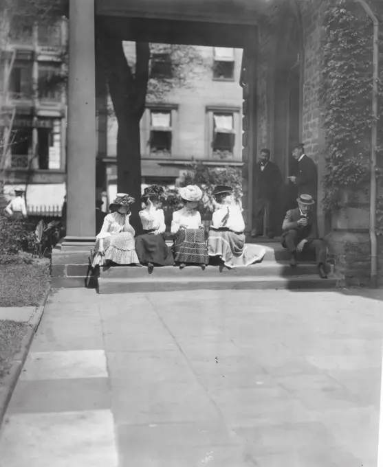 Young women sitting on steps looking at men