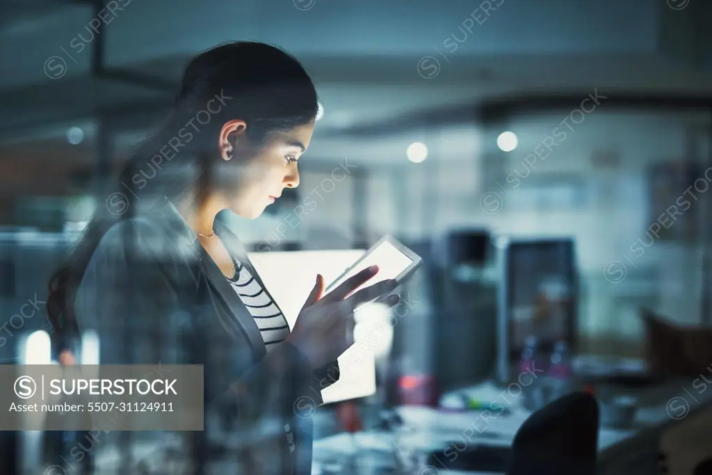 Alone in the office getting work done. Shot of a young businesswoman working late in the office.