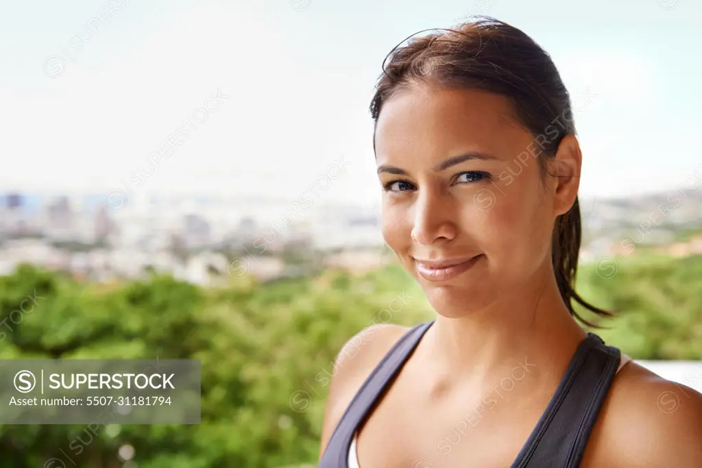 Healthy and happy. Portrait of an attractive young woman in sporty clothing standing on a blacony.