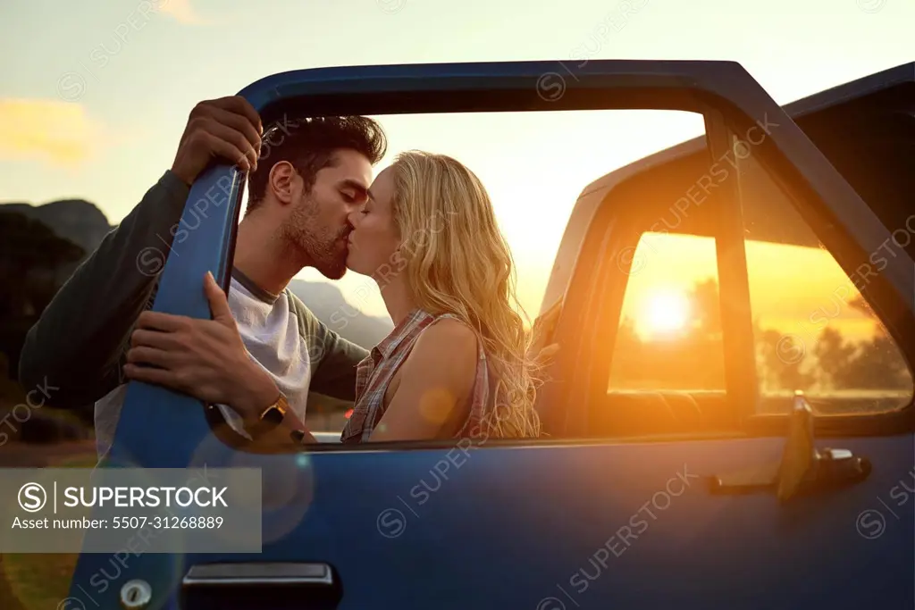 Stopping for a smooch. Shot of an affectionate young couple on a roadtrip.