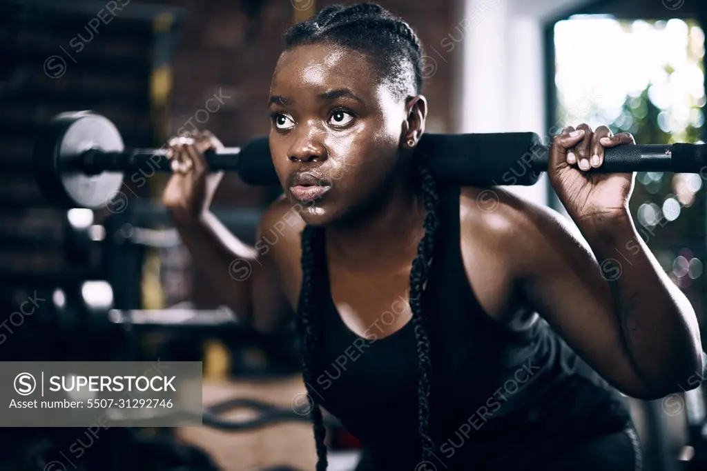 Fully focused. Full length shot of an attractive young female athlete lifting weights in the gym.