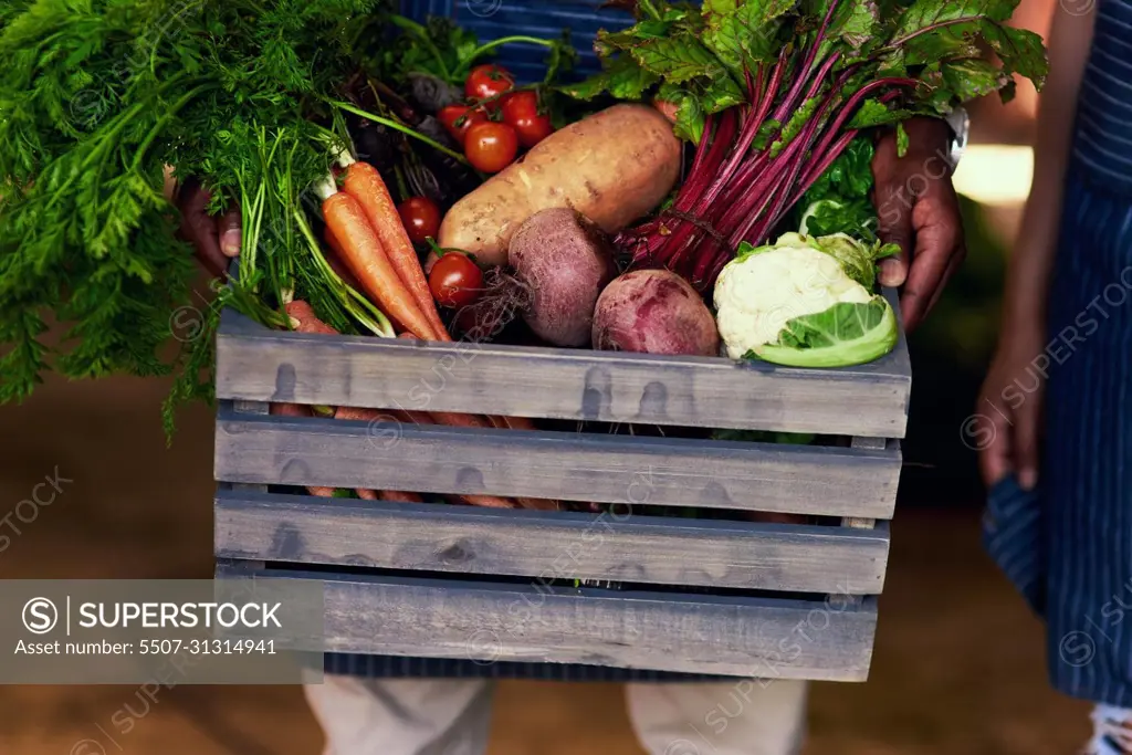 Eat healthy, stay healthy. Cropped shot of an unrecognizable farmer holding a crate full of fresh produce at his farm.