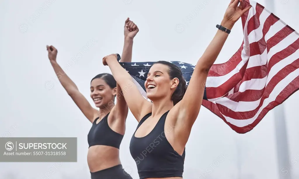 Women run the world. Shot of female athletes celebrating their win while holding a flag.