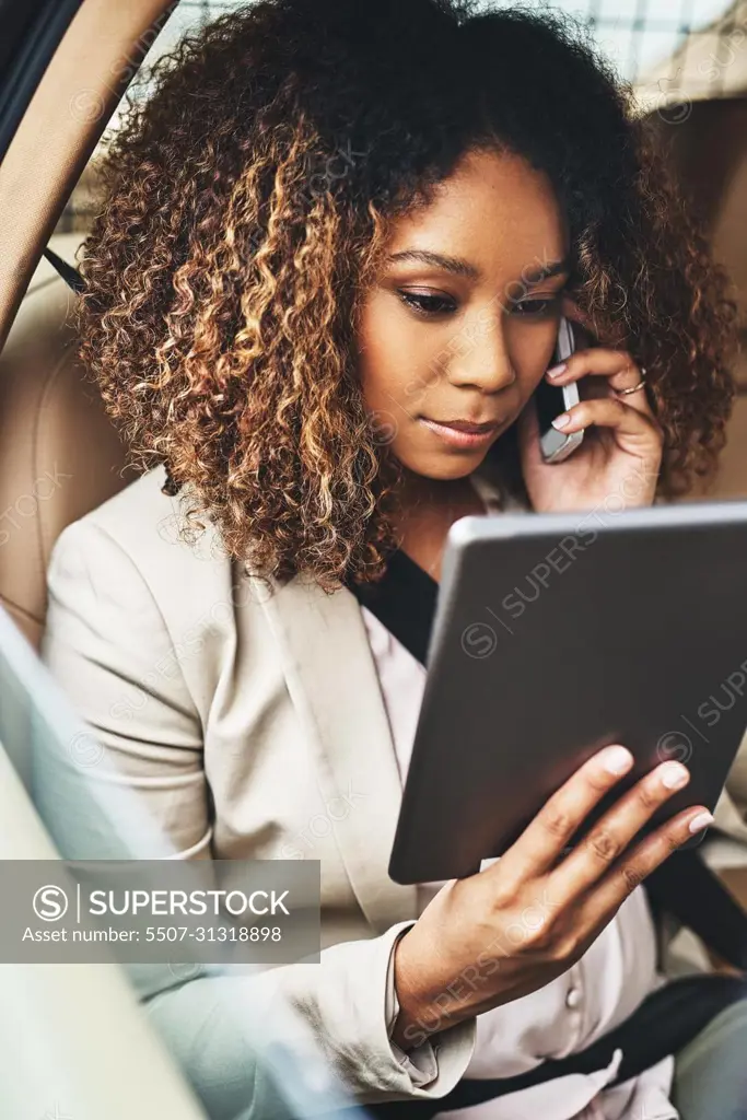 Getting things done even when shes commuting. Shot of an attractive businesswoman on a call and using a tablet during her morning commute.