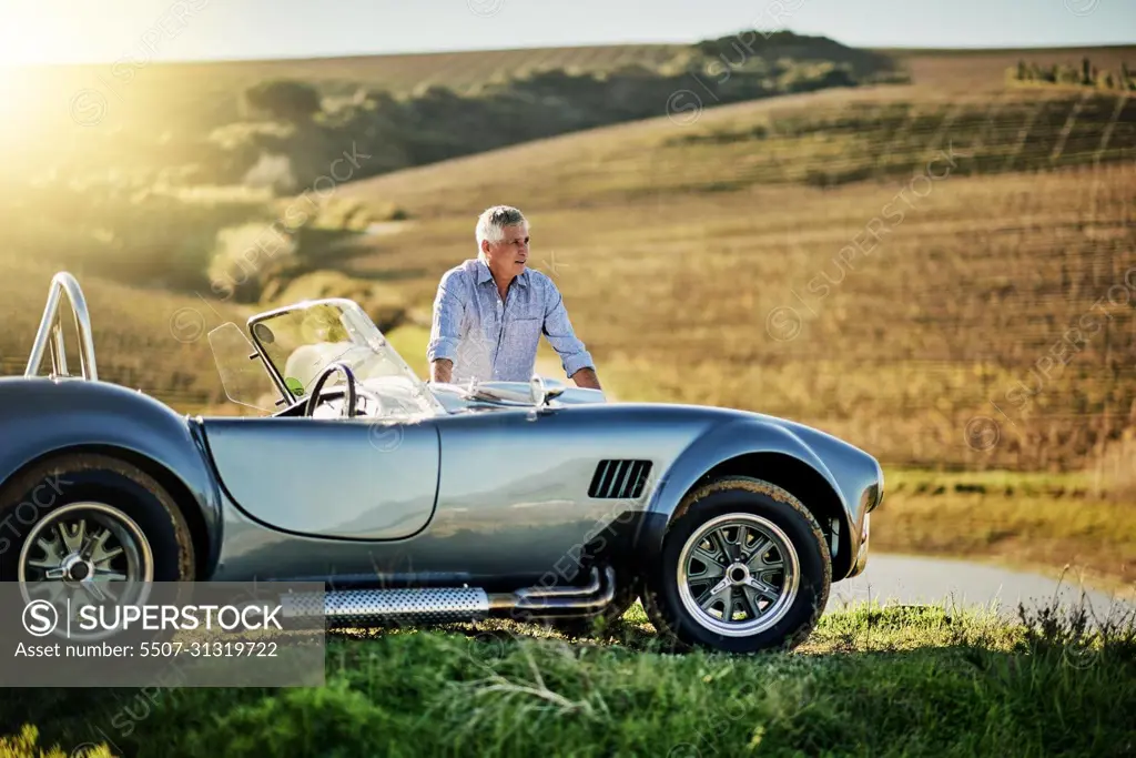 Where to next. Shot of a senior man looking at a map while out on a roadtrip in a convertible.