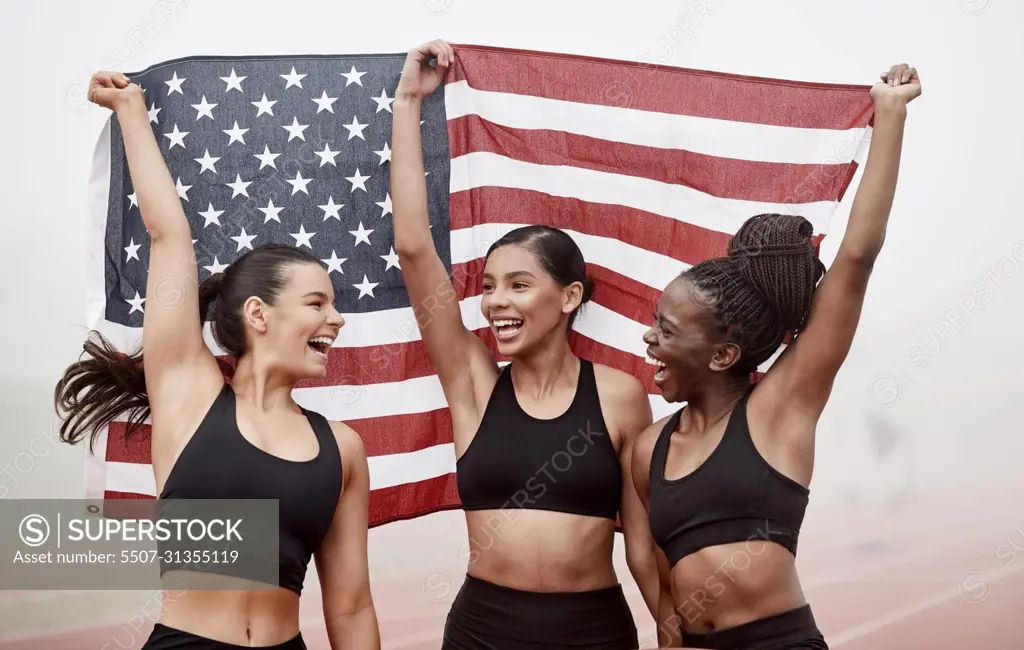 We finally did it. Shot of female athletes celebrating their win while holding a flag.