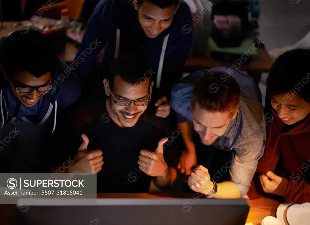 Were gonna win boys. Shot of a group of young man cheering at a monitor in a dark room.