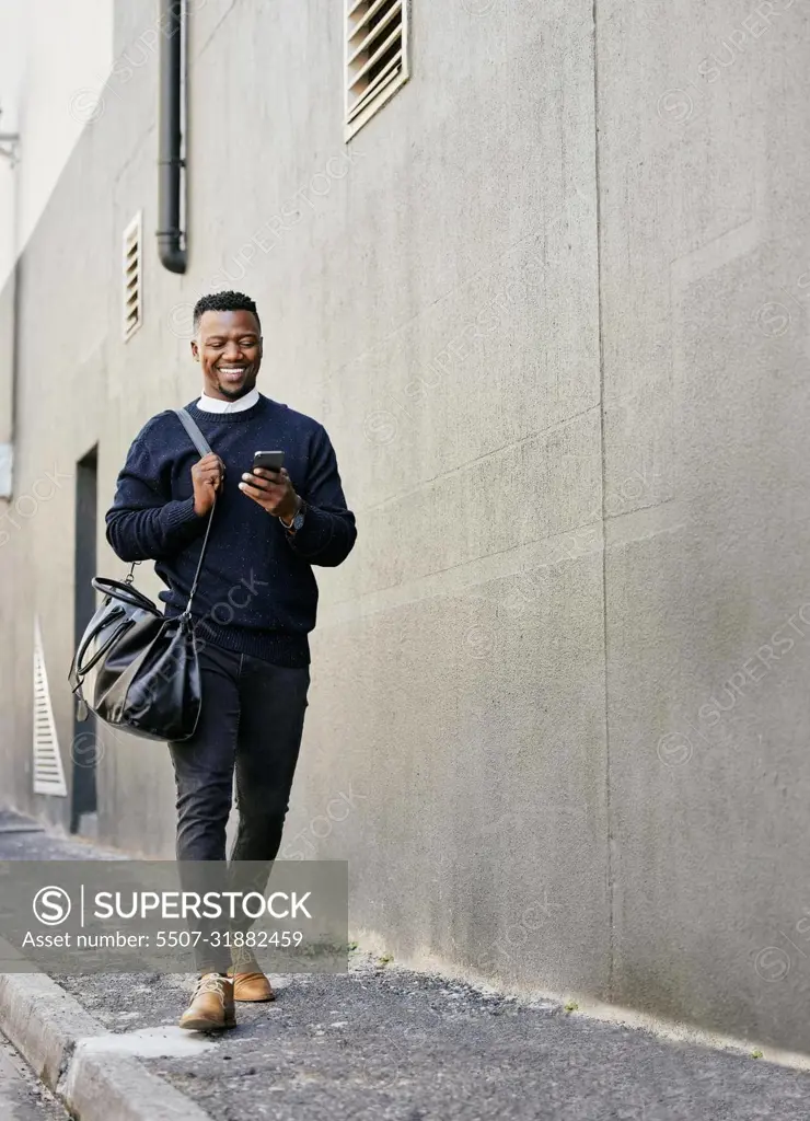 Businessman using his cellphone while walking in the city. Man using cellphone while commuting to work. Using internet while walking outside. Man using internet while commuting