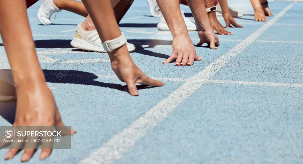 Closeup of determined group of athletes in starting position line to begin sprint or run race on sports track stadium. Hands of diverse sports people ready to compete in track and field olympic event