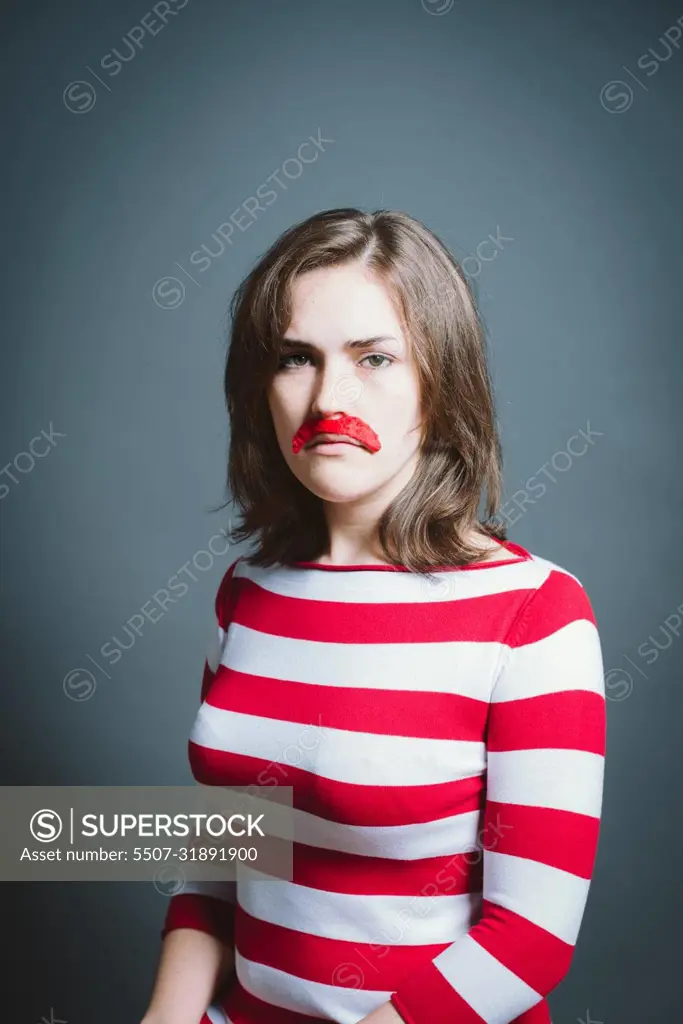 Young woman wearing mask against a grey background in studio. Young woman wearing mask against a grey background in studio.